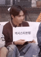 a man is sitting on a couch holding a sign that says ' i 'm sorry ' on it .