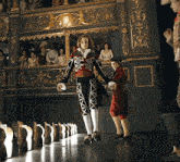 a man in a red and black costume is walking down a stage with a boy in a red and white costume