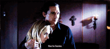 a man and a woman are hugging in a dark room and the man says you 're home