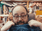 a man wearing glasses and headphones holds a blue shirt in front of a sign that says ' apollo '