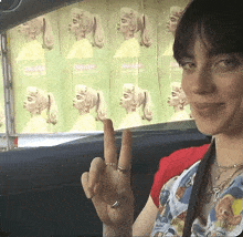 a woman in a car giving the middle finger in front of a poster for billie eilish