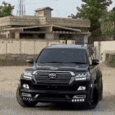 a black toyota land cruiser is parked in front of a large house .
