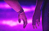 two people holding hands with purple lights behind them