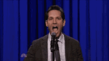 a man in a suit and tie is speaking into a microphone .