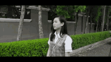 a girl in a school uniform is walking down a sidewalk .