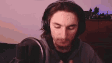 a man wearing headphones is sitting in front of a microphone in a room .