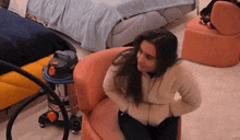 a woman is sitting on a chair next to a vacuum cleaner