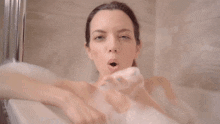 a woman in a bathtub blowing soap bubbles in the air