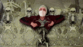 a man wearing a mask is surrounded by skeletons in a cemetery