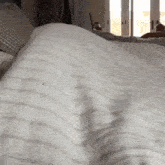 a bed with a white striped comforter and pillows on it