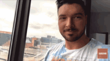a man stands in front of a window wearing a hard rock shirt