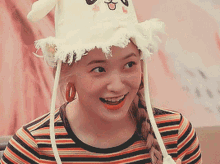 a woman wearing a striped shirt and a hat is smiling