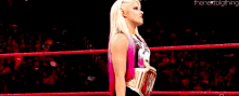 a female wrestler is standing in a wrestling ring holding a trophy .