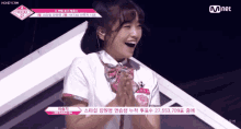 a girl is laughing with her hands folded in front of her face