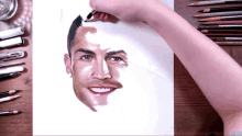 a person is drawing a picture of a man 's face with a pencil on a piece of paper
