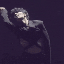 a man in a black jacket is dancing with his arms outstretched