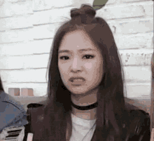 a woman with long hair is wearing a choker and a bun on her head .