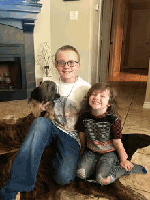 a boy with glasses is holding a puppy while sitting next to another boy