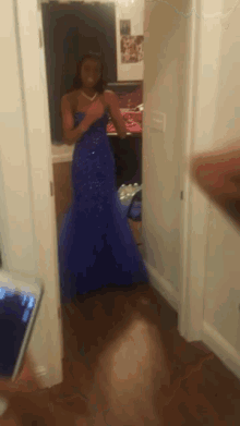 a woman in a blue dress is taking a selfie