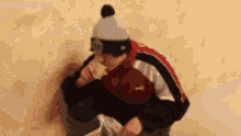 a man wearing a red jacket and a white hat is eating a sandwich