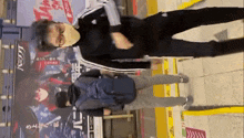 a man wearing a mask is standing next to another man in front of a sign that says ' a ' on it