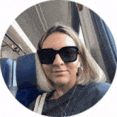 a woman wearing sunglasses and headphones is sitting on a train .