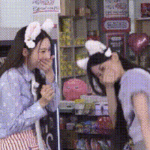 two girls wearing bunny ears covering their mouths in a store