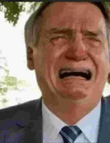 a man in a suit and tie is crying with his mouth open and his eyes closed .