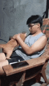 a young man is sitting in a wooden chair holding a cat .
