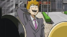 a man in a suit and tie is laughing with his hand behind his head .