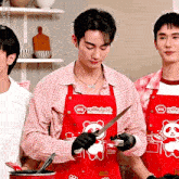 a man wearing a red apron with a teddy bear on it is holding a knife