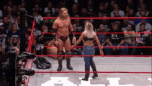 a man and a woman are standing in a wrestling ring with the word all on the ring
