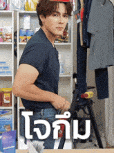 a man in a blue shirt is standing in front of a sign that says ' ใจ กับ ' on it