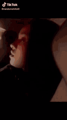 a close up of a person 's face in a dark room with a light shining through the window .
