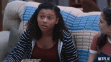 a woman sitting on a couch with a blanket that says netflix