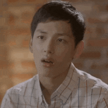 a young man in a plaid shirt makes a surprised face