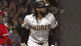 a padres baseball player stands in front of a crowd during a game