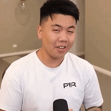 a man wearing a white t-shirt with the word pir on it is smiling .