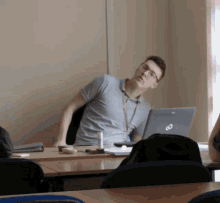 a man sitting at a desk with a laptop that says ' infinity ' on it