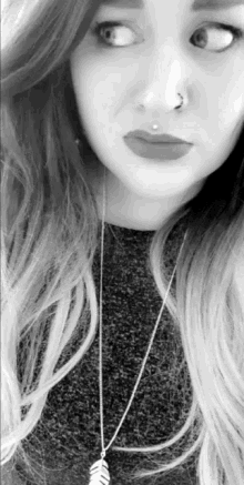 a black and white photo of a woman with a nose ring and a feather necklace