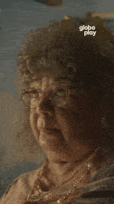 an older woman is sitting at a table with a globe play advertisement in the background