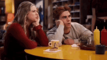 a man and a woman are sitting at a table in a restaurant talking to each other .