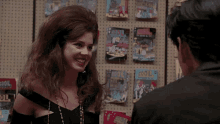a woman is smiling in front of a display of cool magazines