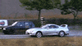 a silver sports car is driving next to a black car with a sticker on the back that says ' ziggy '