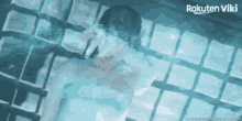 a man and woman are swimming in a pool with rakuten viki on the bottom