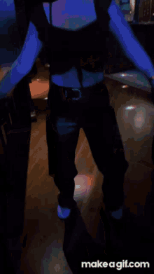 a woman is dancing in a dark room with purple lights behind her