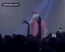 a man is singing into a microphone while a crowd watches .