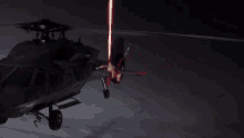 a helicopter is flying in the dark with a red light coming out of it