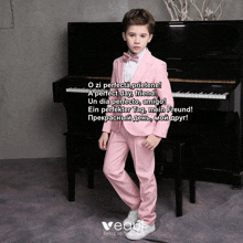 a young boy in a pink suit is standing in front of a piano with a poem in another language