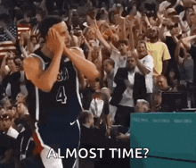 a basketball player with the number 4 on his jersey is standing in front of a crowd of people and applauding .